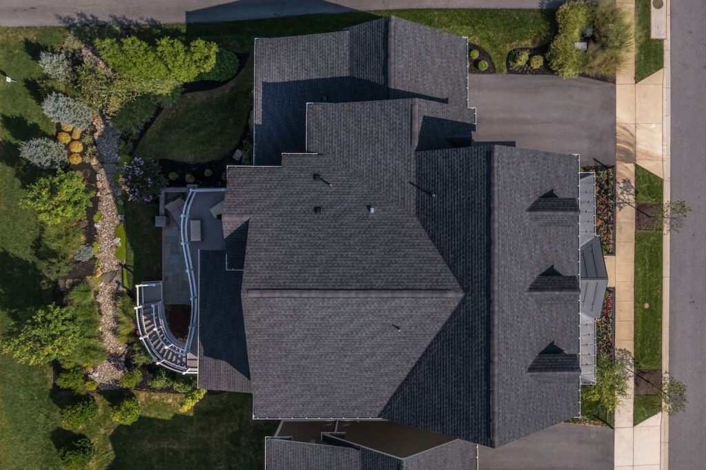 Aerial top down view of a complex hip and valley pitched roof with three dormers and shingled roof