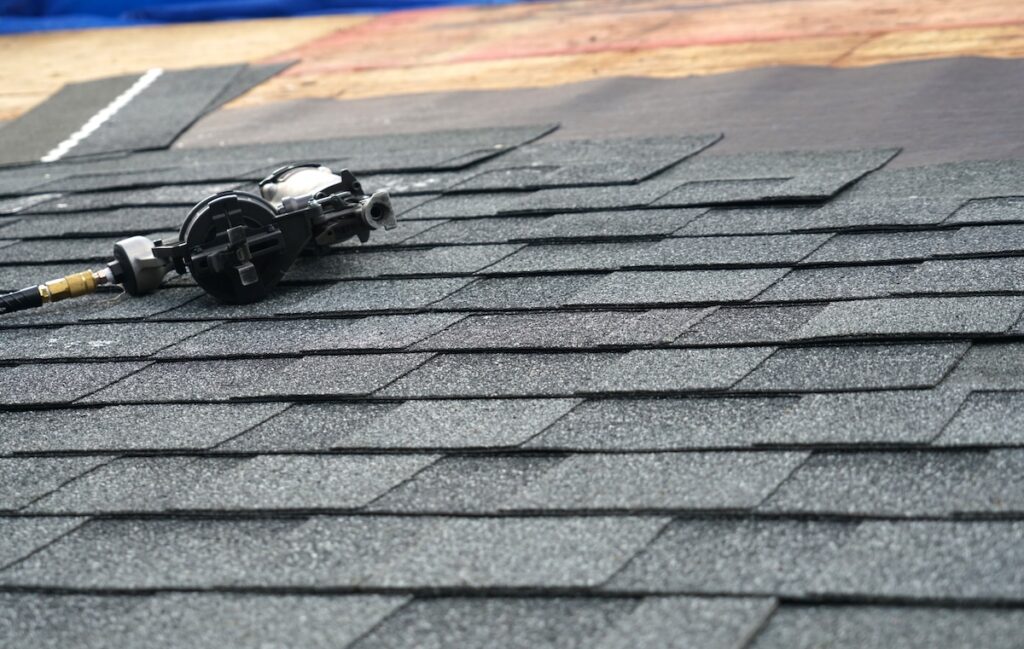 close up on nail gun on the roof shingle