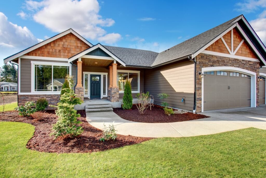 Large modern house with walkway and lots of grass.