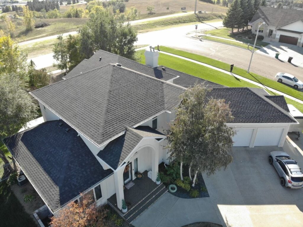 white house with dark asphalt shingle roof surrounded by trees