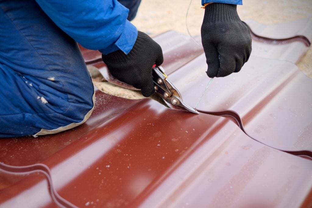Worker use scissors for cutting of metal roofing sheet.