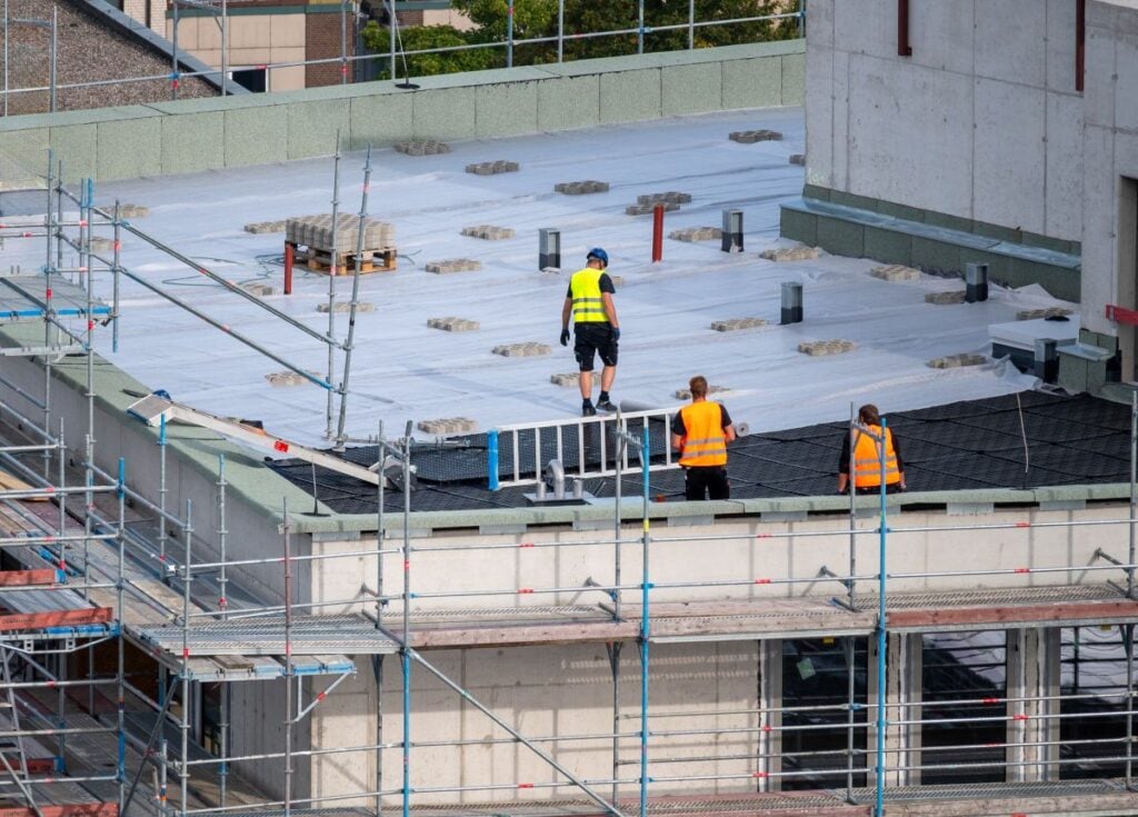 commercial flat roof workers installing big building