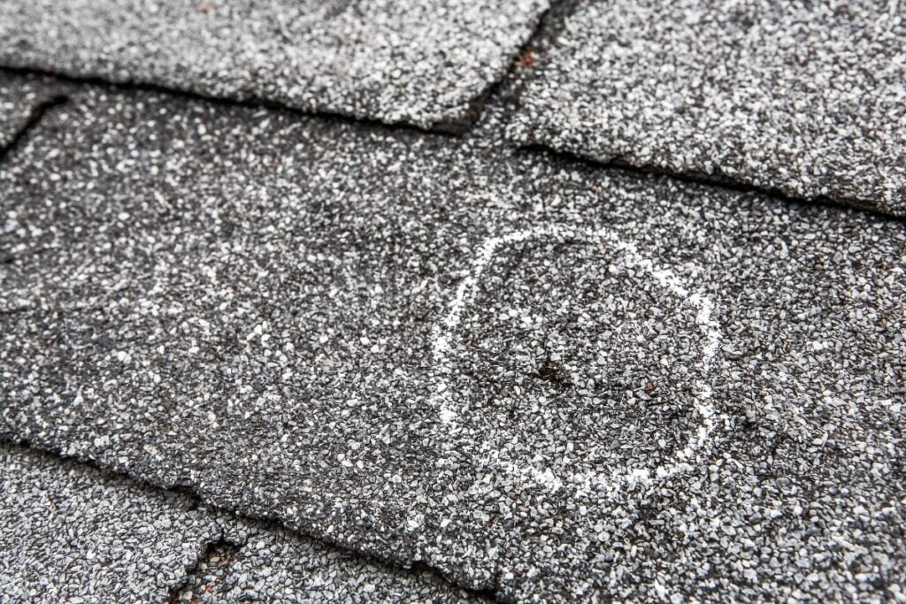 signs of hail damage on roof hole on shingle after storm