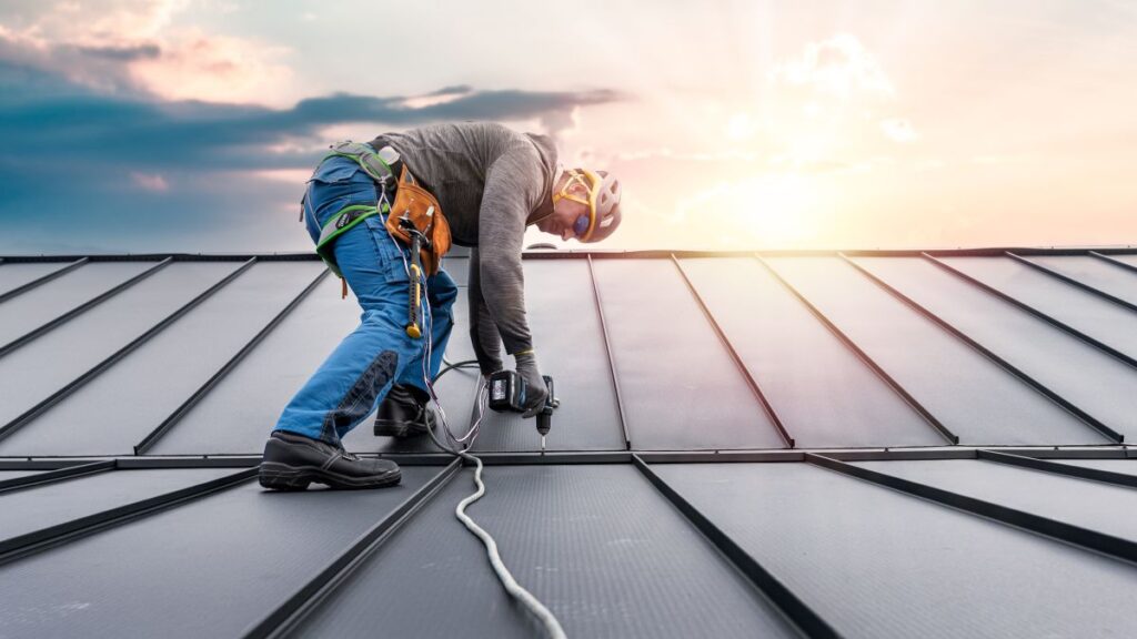 standing seam metal roof worker using nail gun to repair metallic roof