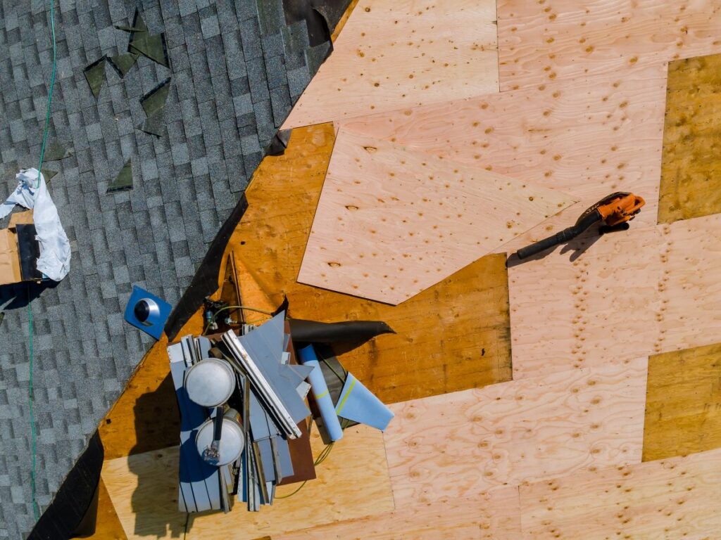 A worker replace shingles on the roof of a home repairing the roof of home
