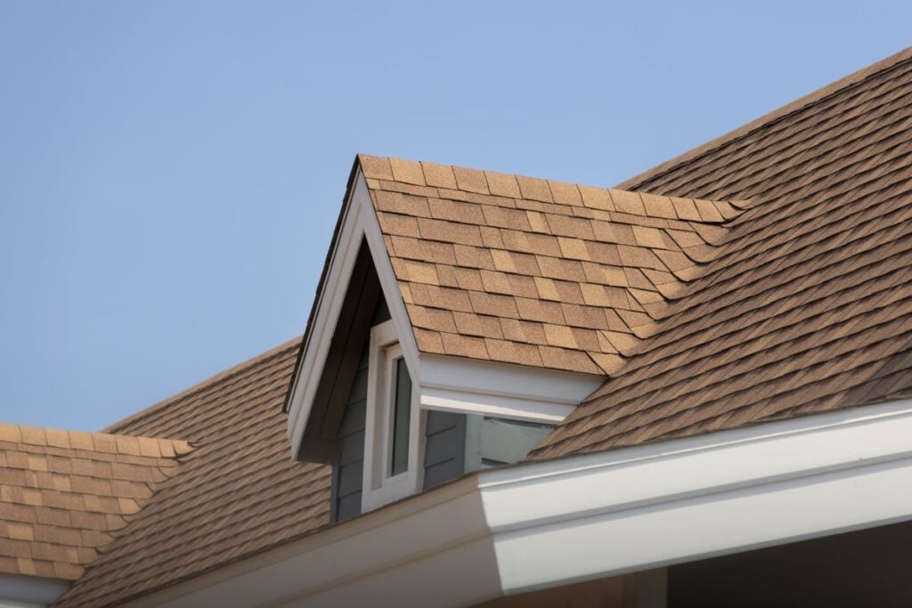 Roof shingles with garret house on top of the house, dark brown asphalt tiles on the roof